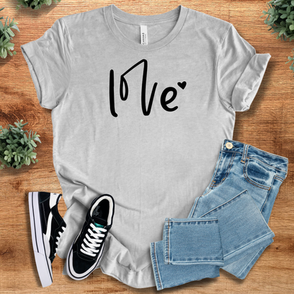 Pink t-shirt with '' text, flat lay styled on a wooden surface.