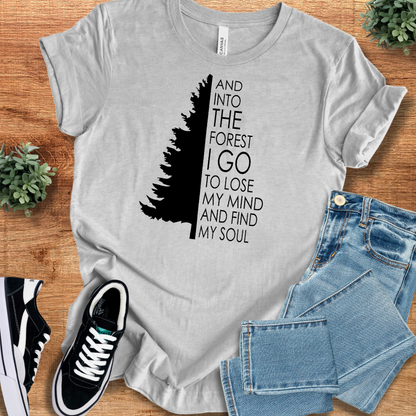 Athletic-heather t-shirt with 'Into The Forest I Go T‑Shirt' text, flat lay styled on a wooden surface.
