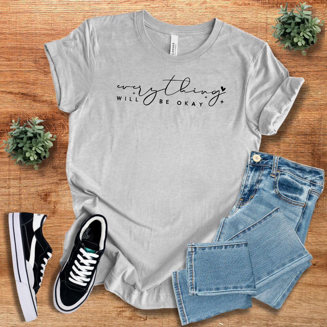 Gray 'Everything Will Be Ok' t-shirt with black script text, paired with jeans and sneakers. A comfortable and stylish unisex casual tee.