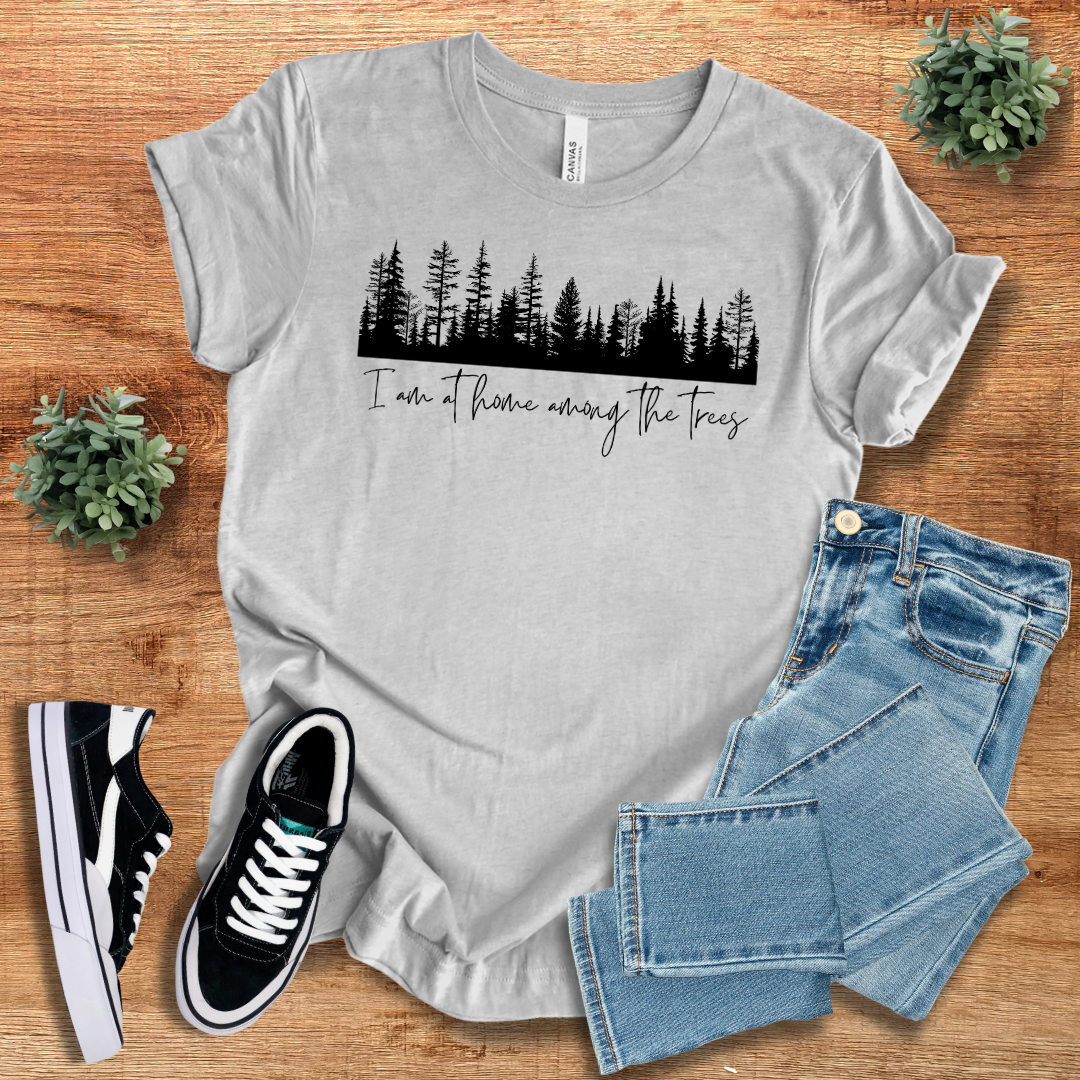 Heather gray nature lover T-shirt with a black tree silhouette and 'I'm At Home Among The Trees' text. A lightweight and breathable outdoor tee.