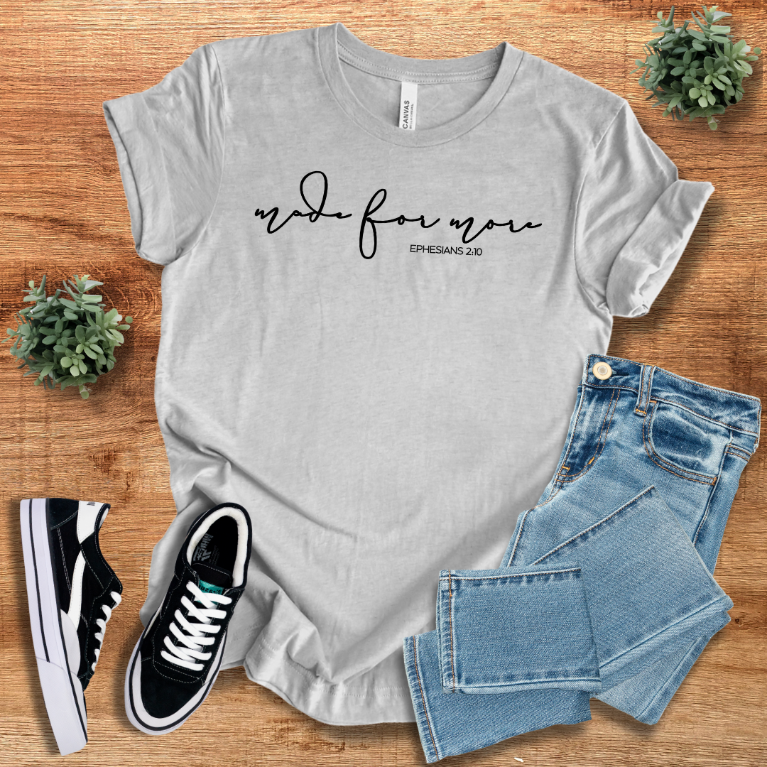 Heather gray Made for More Graphic Tshirt with black script text, laid flat with denim jeans and sneakers. A soft and stylish unisex tee.