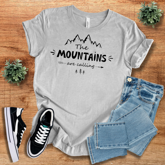 Heather gray 'The Mountains Are Calling' T-shirt with black mountain design. Casual and trendy outdoor adventure tee for nature lovers.