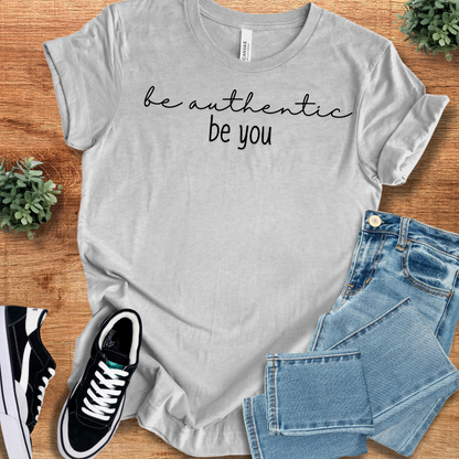Heather-mauve t-shirt with '' text, flat lay styled on a wooden surface.