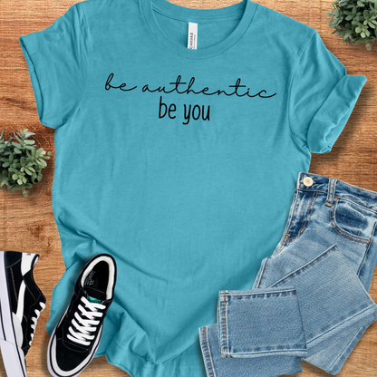 Heather-mauve t-shirt with '' text, flat lay styled on a wooden surface.