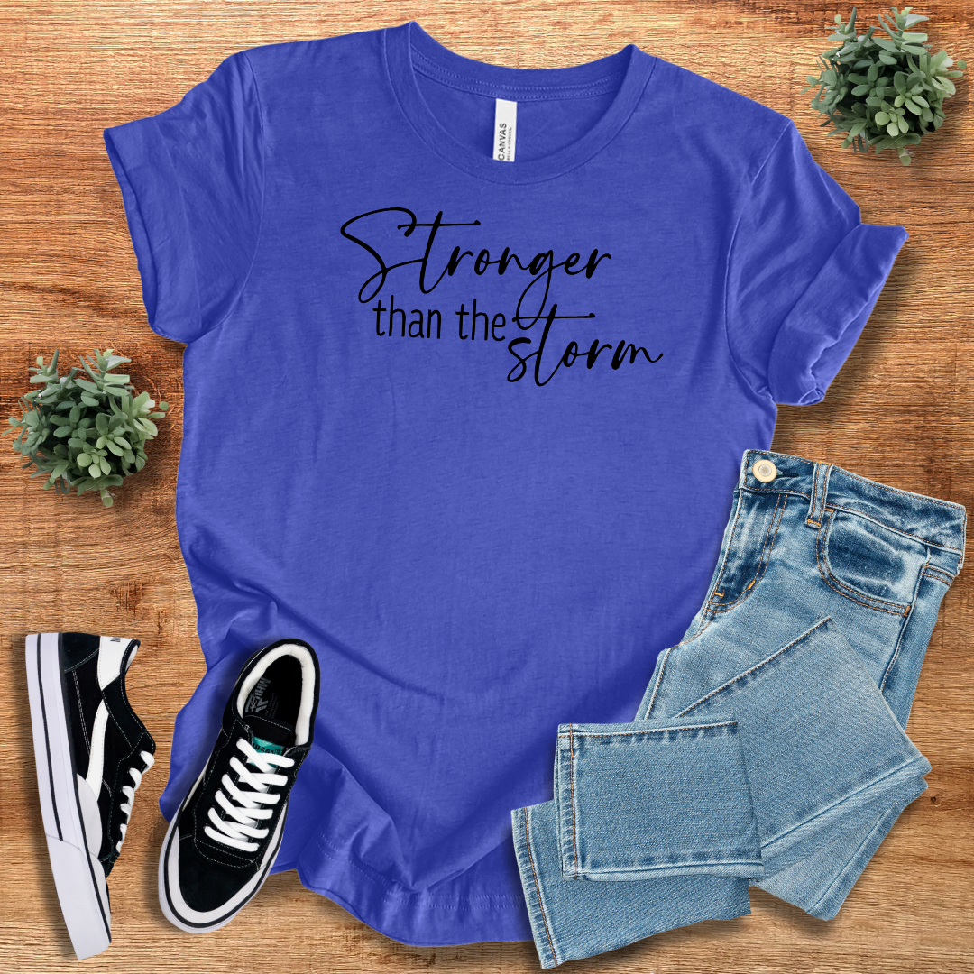 Royal blue Stronger Than The Storm T-Shirt with black script text, styled with denim jeans and sneakers for a bold, empowering fashion choice.