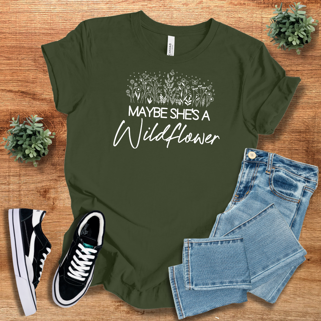 Olive green wildflower graphic tee with 'Maybe She's a Wildflower' text, perfect for nature lovers and free spirits. Soft cotton fabric for casual wear.