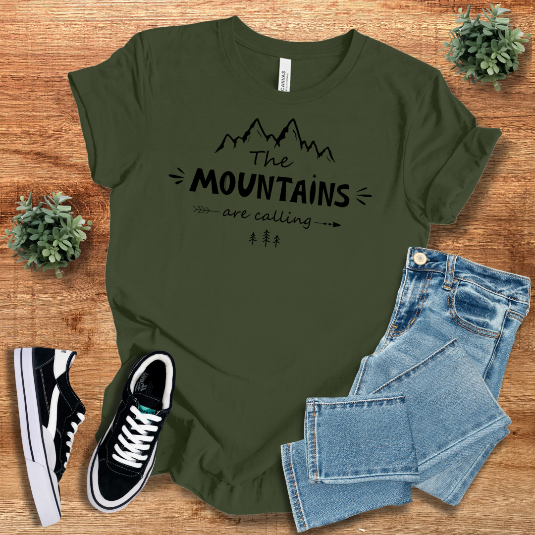Olive green 'The Mountains Are Calling' T-shirt featuring black mountain design. Trendy outdoor adventure tee for hiking and casual wear.