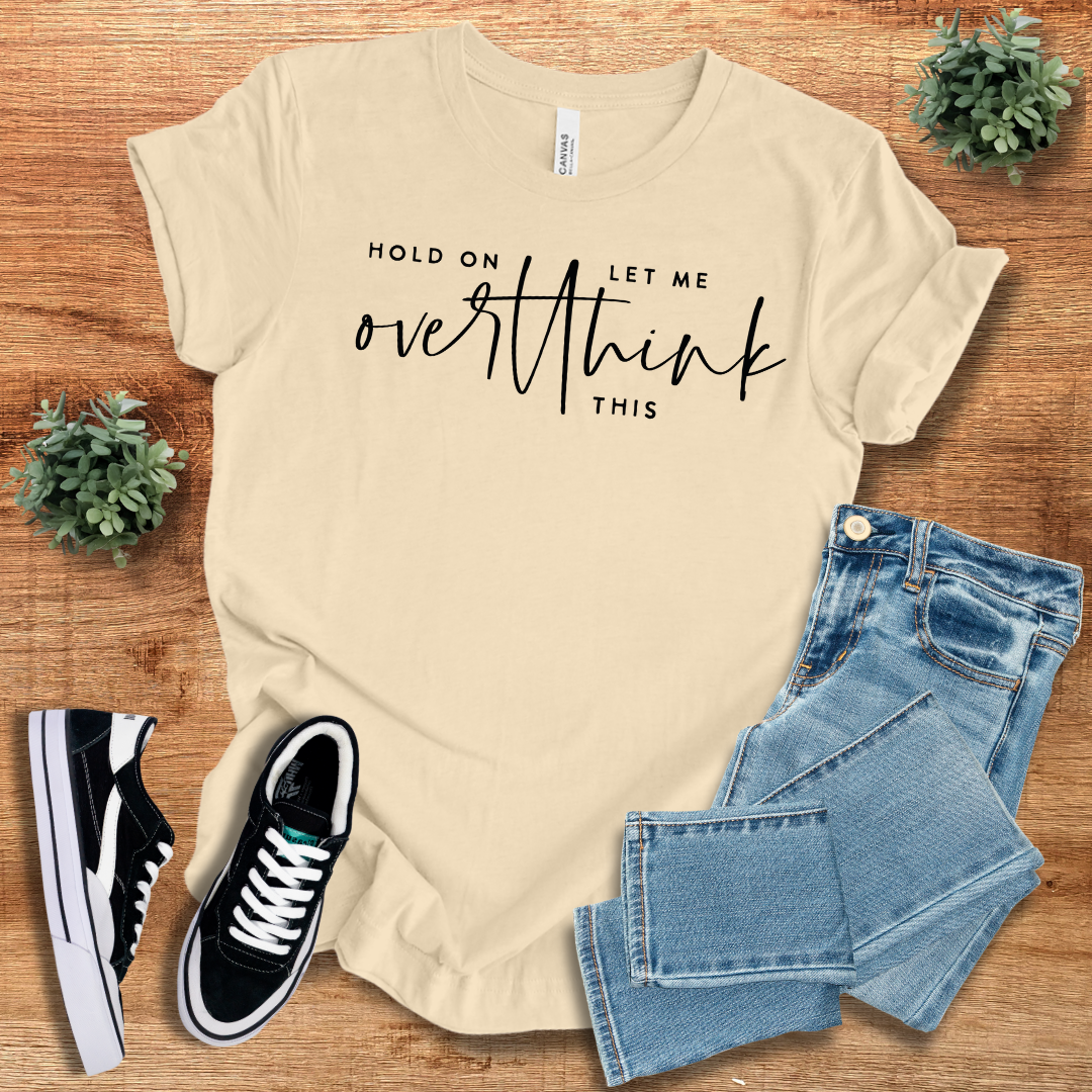 Cream 'Hold On Let Me Overthink This' t-shirt with black script text. Comfortable cotton blend, regular fit, and stylish for everyday wear.
