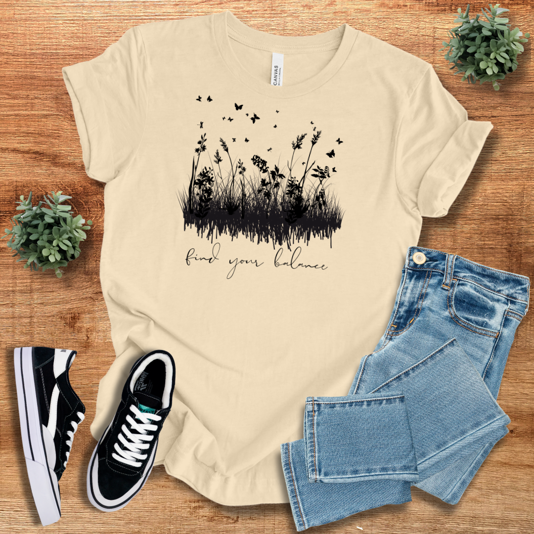 Beige Find Your Balance T-shirt with black wildflower and bird design. A sustainable and stylish cotton tee for casual layering.