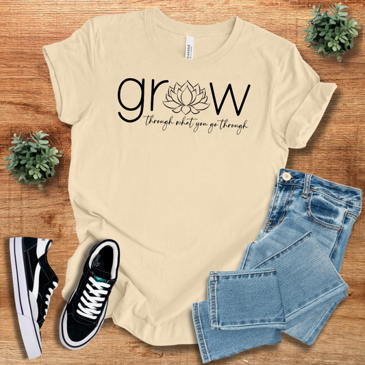 Beige 'Grow Through What You Go Through' t-shirt featuring a lotus design. Comfortable cotton fabric, unisex fit, ideal for everyday wear.