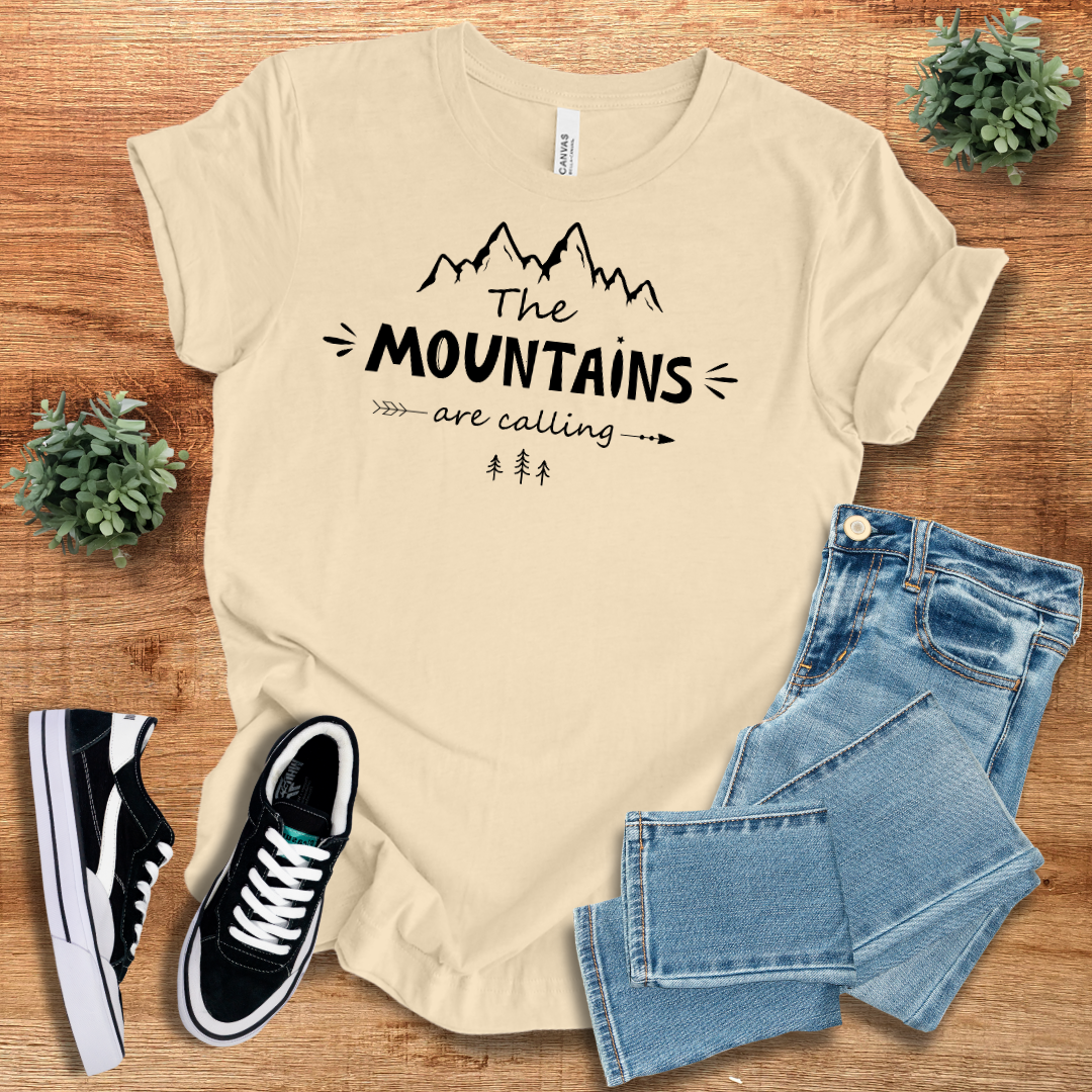 Cream 'The Mountains Are Calling' T-shirt with black mountain graphic. Soft and breathable cotton tee, perfect for outdoor adventures.