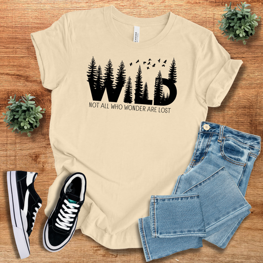 Beige Wild Not All Who Wonder Are Lost t-shirt with a black forest silhouette. A soft and stylish tee for outdoor lovers and explorers.