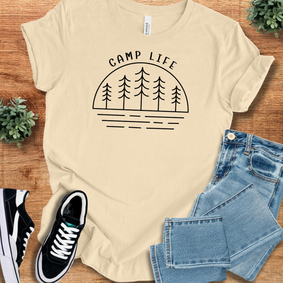 Soft-cream t-shirt with 'Camp Life T‑Shirt' text, flat lay styled on a wooden surface.