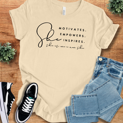 Beige unisex t-shirt featuring 'She Motivates Empowers Inspires' text. Made from breathable cotton with a crew neck and regular fit for versatile styling.