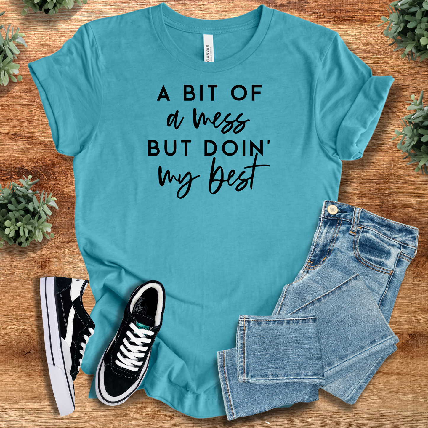 Heather-mauve t-shirt with '' text, flat lay styled on a wooden surface.