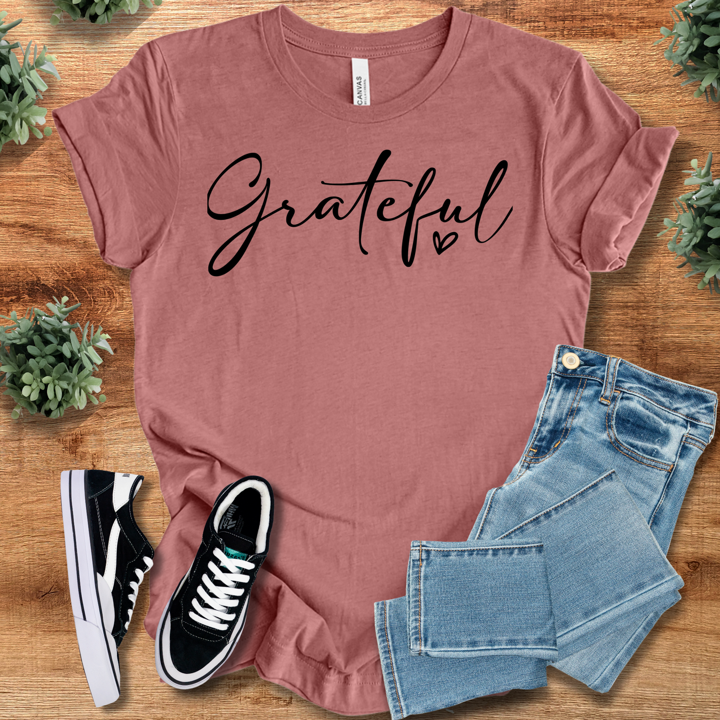 White t-shirt with '' text, flat lay styled on a wooden surface.