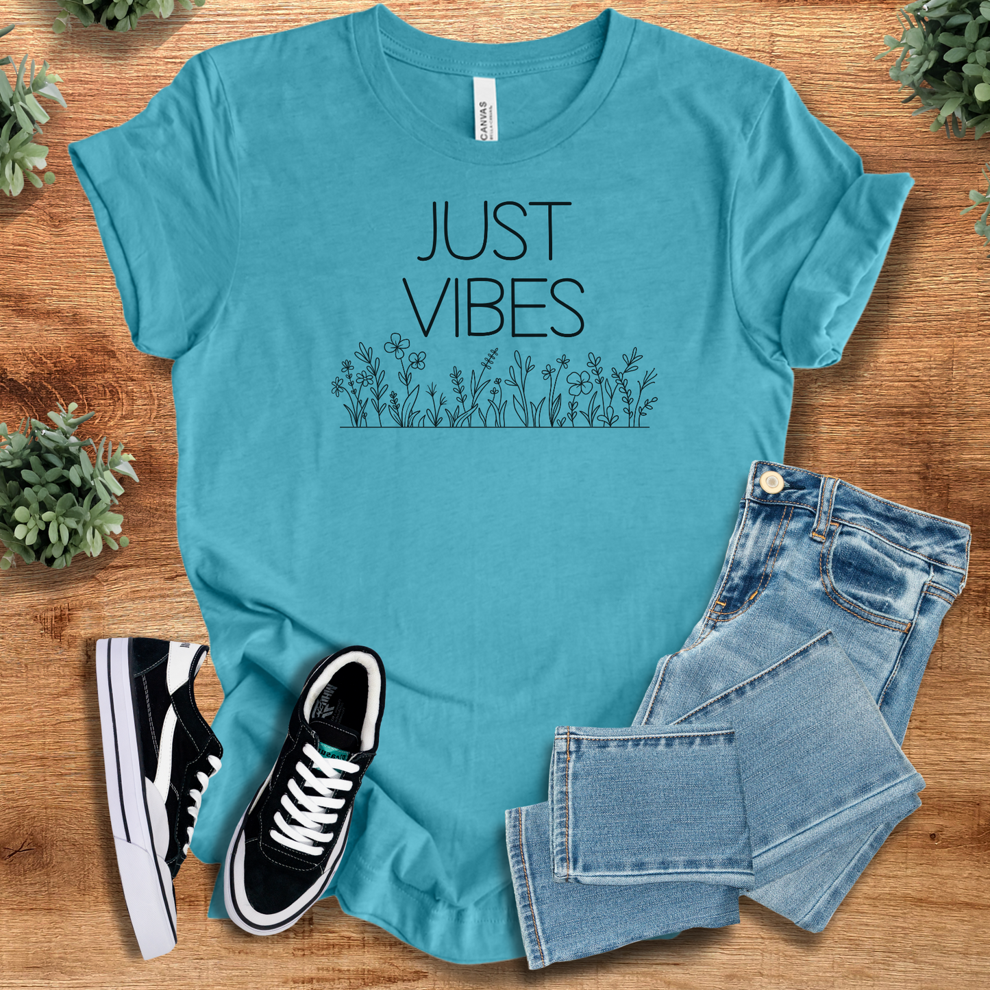 Aqua blue Just Vibes Wildflower T‑Shirt made with Bella+Canvas 3001. Soft nature-inspired tee styled with casual denim and sneakers.