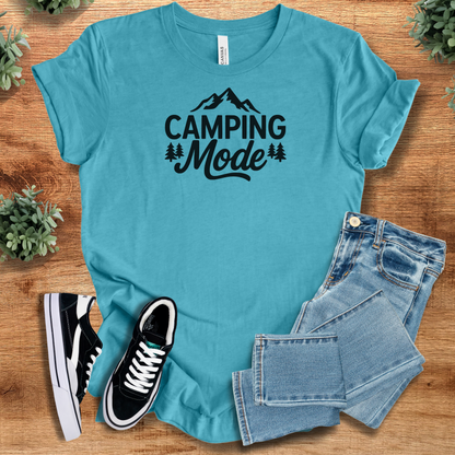 Heather-aqua t-shirt with 'Camping Mode Adventure T‑Shirt' text, flat lay styled on a wooden surface.