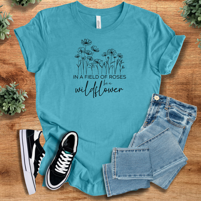 Military-green t-shirt with '' text, flat lay styled on a wooden surface.