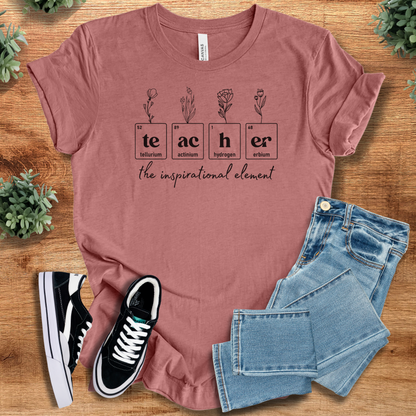 Heather-mauve t-shirt with 'Teacher Element Tee T‑Shirt' text, flat lay styled on a wooden surface.
