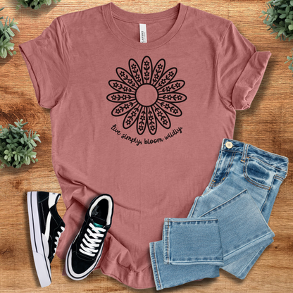Heather-mauve t-shirt with 'Live Simply, Bloom Wildly T‑Shirt' text, flat lay styled on a wooden surface.