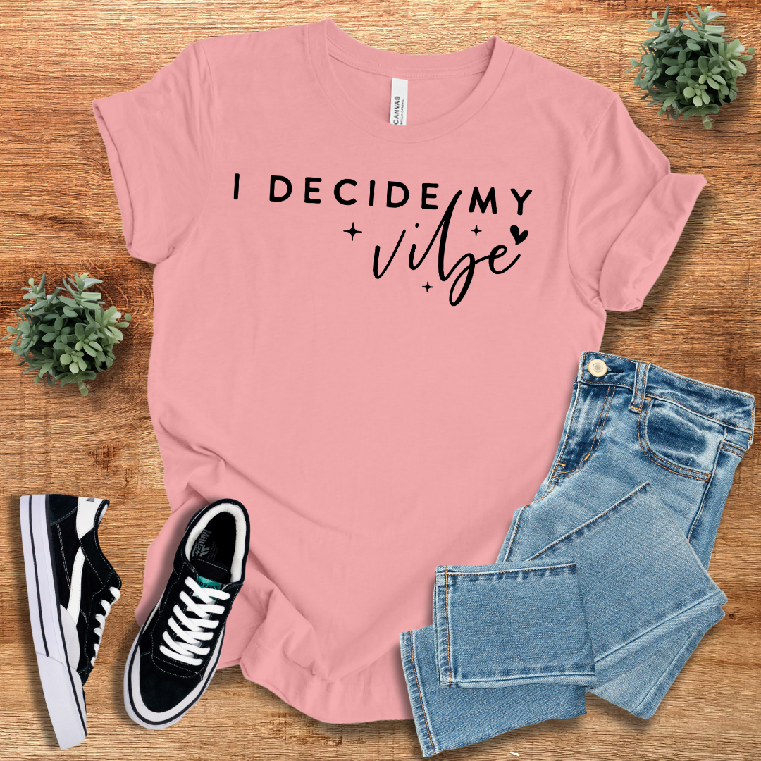 Light pink 'I Decide My Vibe' t-shirt with black text, paired with jeans and sneakers. Comfortable cotton tee for casual everyday style.