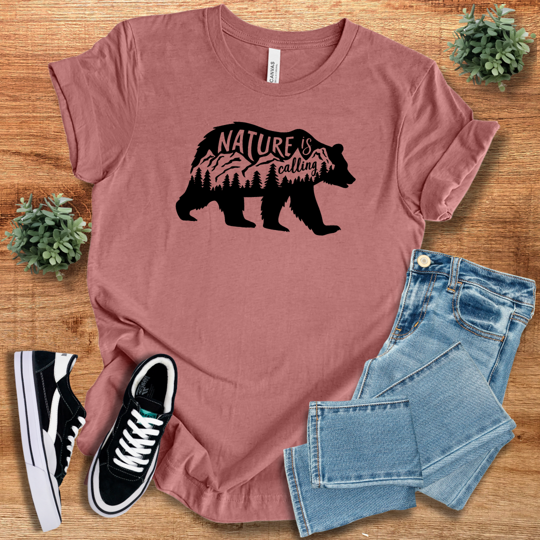Rust-colored 'Nature Is Calling' t-shirt featuring a black bear silhouette with mountain and forest design. Perfect for nature lovers and adventurers.