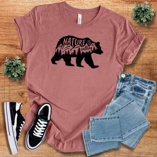 Rust-colored 'Nature Is Calling' t-shirt featuring a black bear silhouette with mountain and forest design. Perfect for nature lovers and adventurers.