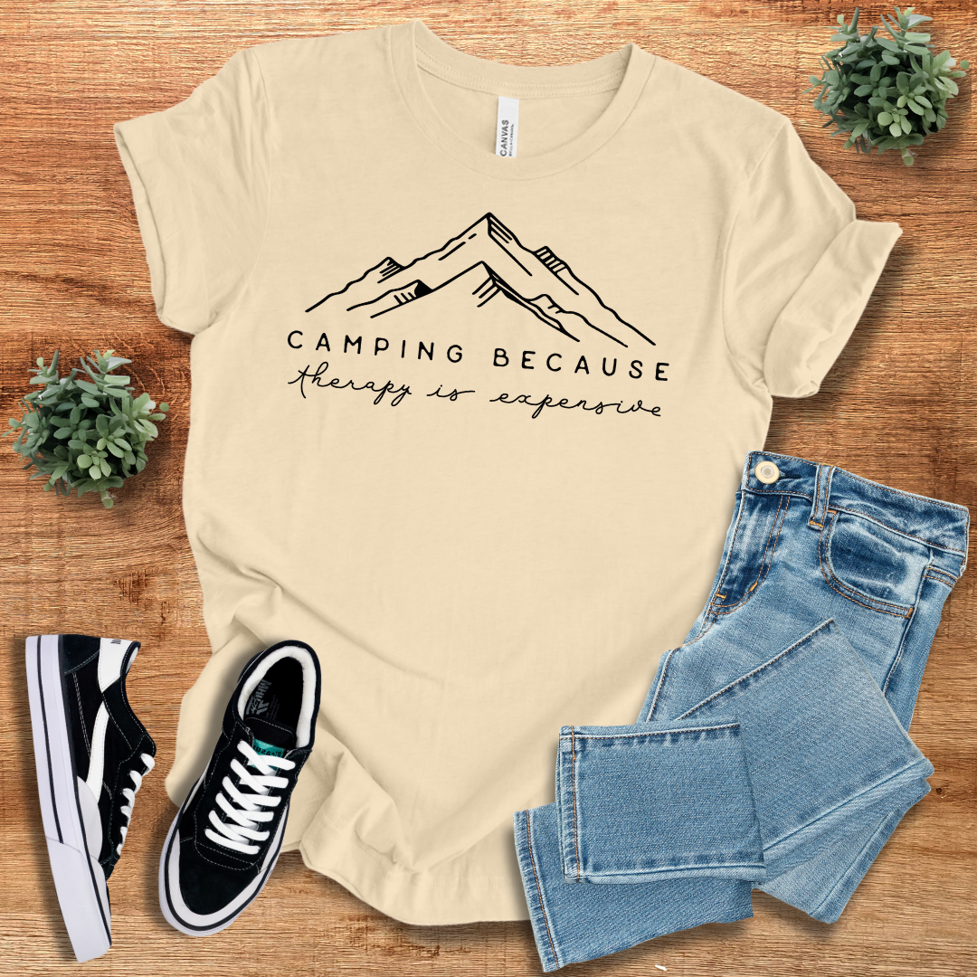Beige 'Camping Because Therapy is so Expensive' t-shirt with minimalist mountain design. Comfortable cotton tee for camping and hiking lovers.