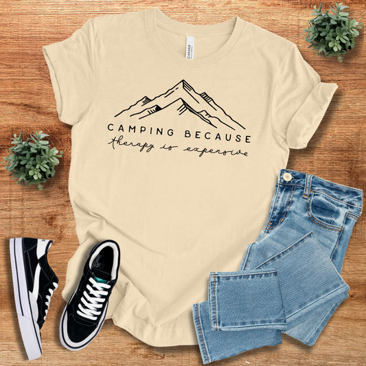 Beige 'Camping Because Therapy is so Expensive' t-shirt with minimalist mountain design. Comfortable cotton tee for camping and hiking lovers.