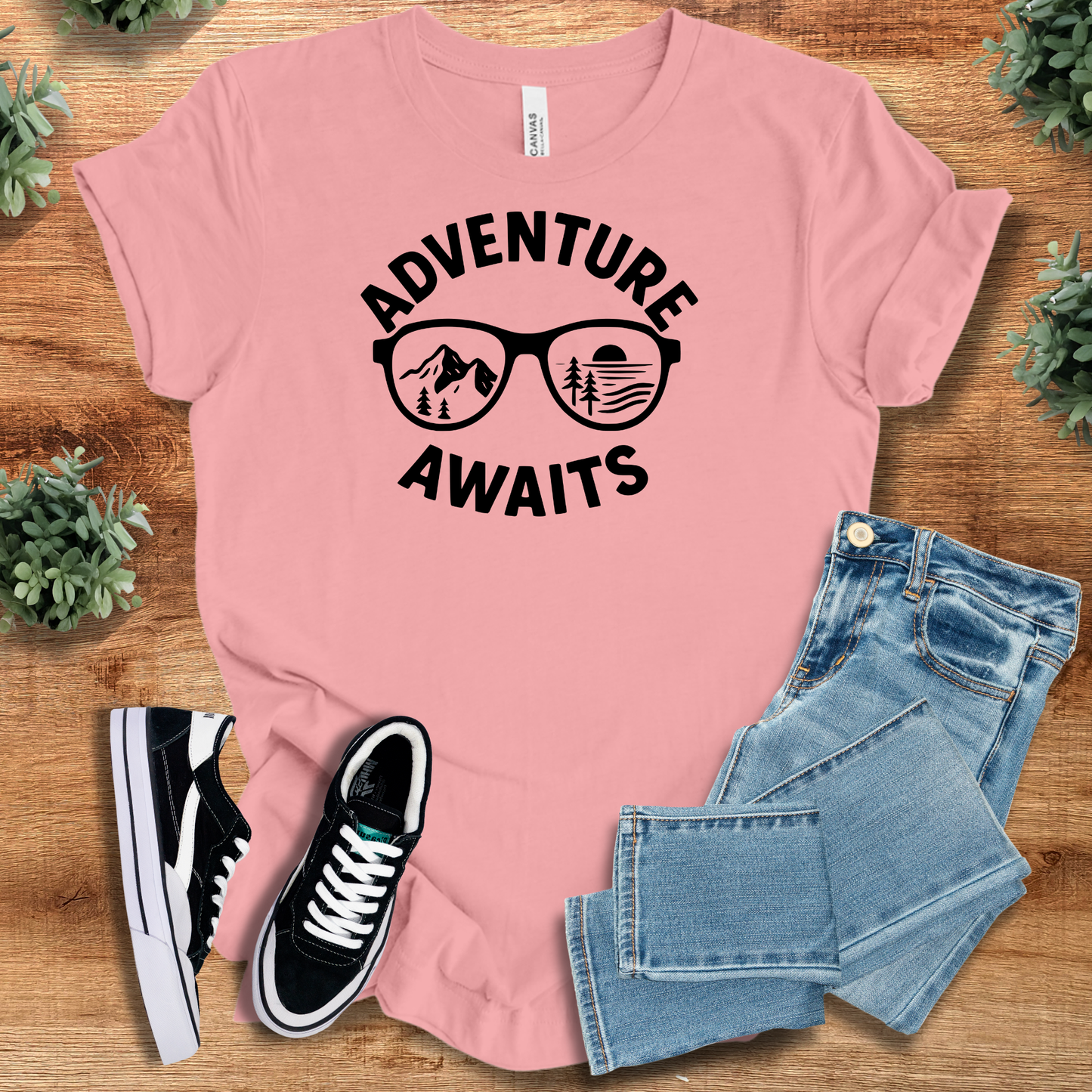 Black t-shirt with '' text, flat lay styled on a wooden surface.