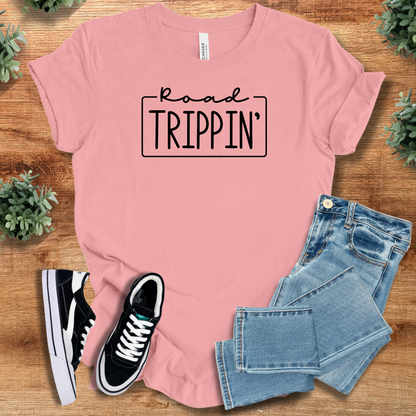 White t-shirt with '' text, flat lay styled on a wooden surface.
