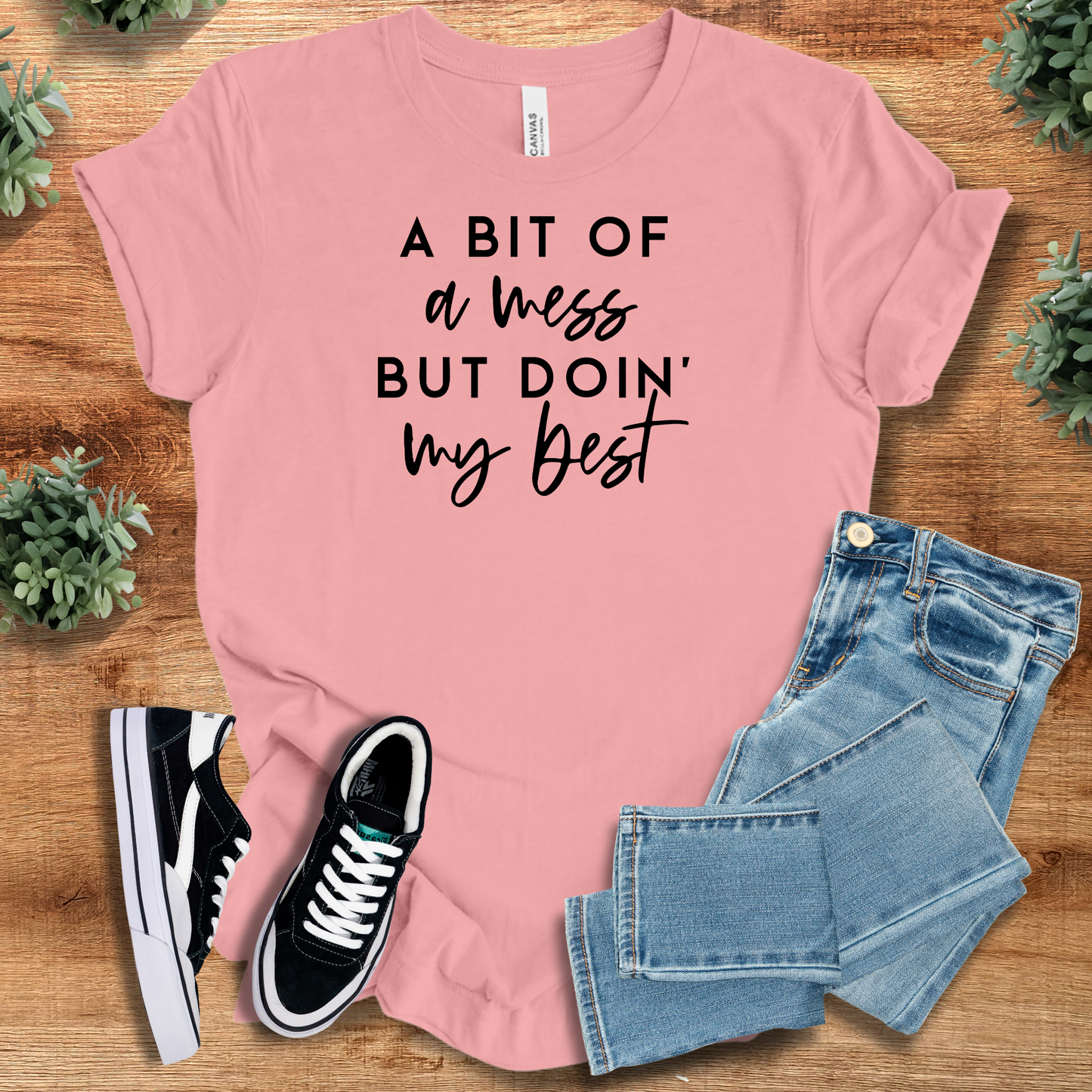 Heather-mauve t-shirt with '' text, flat lay styled on a wooden surface.