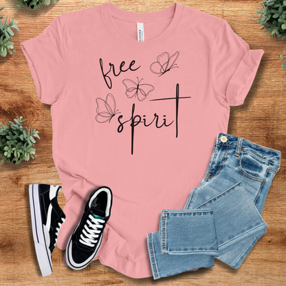 Pink t-shirt with 'Free Spirit T‑Shirt' text, flat lay styled on a wooden surface.