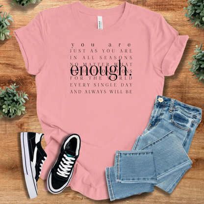 White t-shirt with '' text, flat lay styled on a wooden surface.