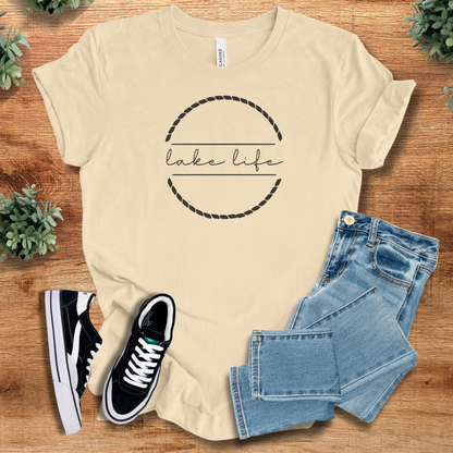 Military-green t-shirt with '' text, flat lay styled on a wooden surface.