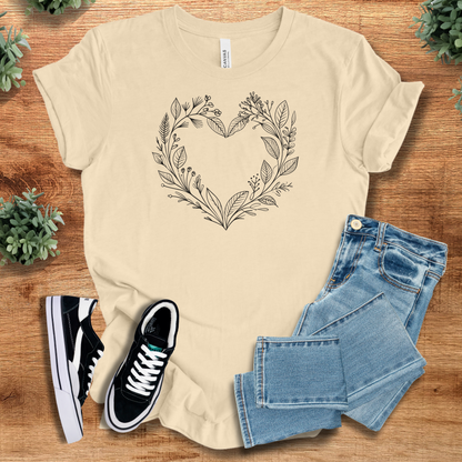 Soft-cream t-shirt with 'Flower Heart T‑Shirt' text, flat lay styled on a wooden surface.