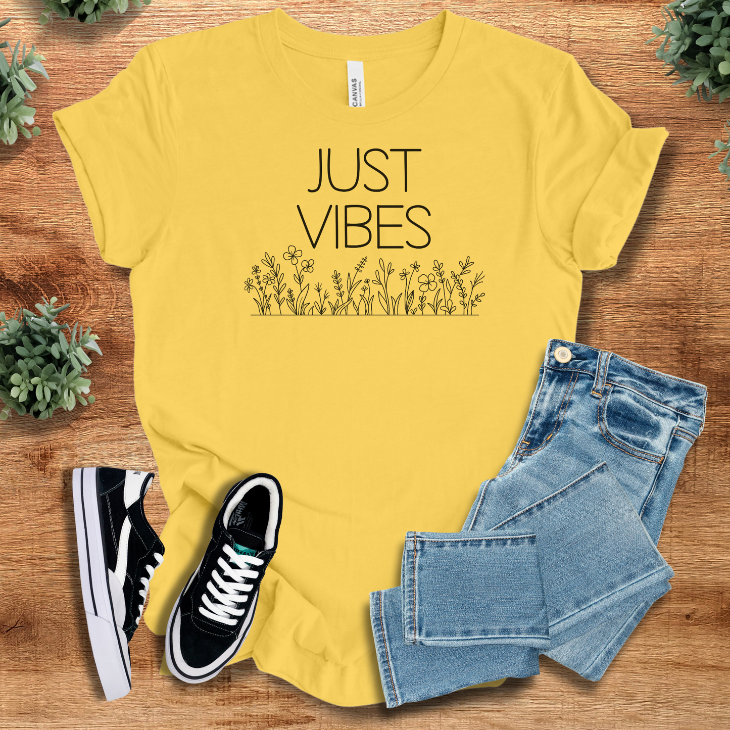 Just Vibes Wildflower T‑Shirt in yellow on soft Bella+Canvas 3001 fabric. Minimalist floral graphic tee styled with jeans and sneakers.
