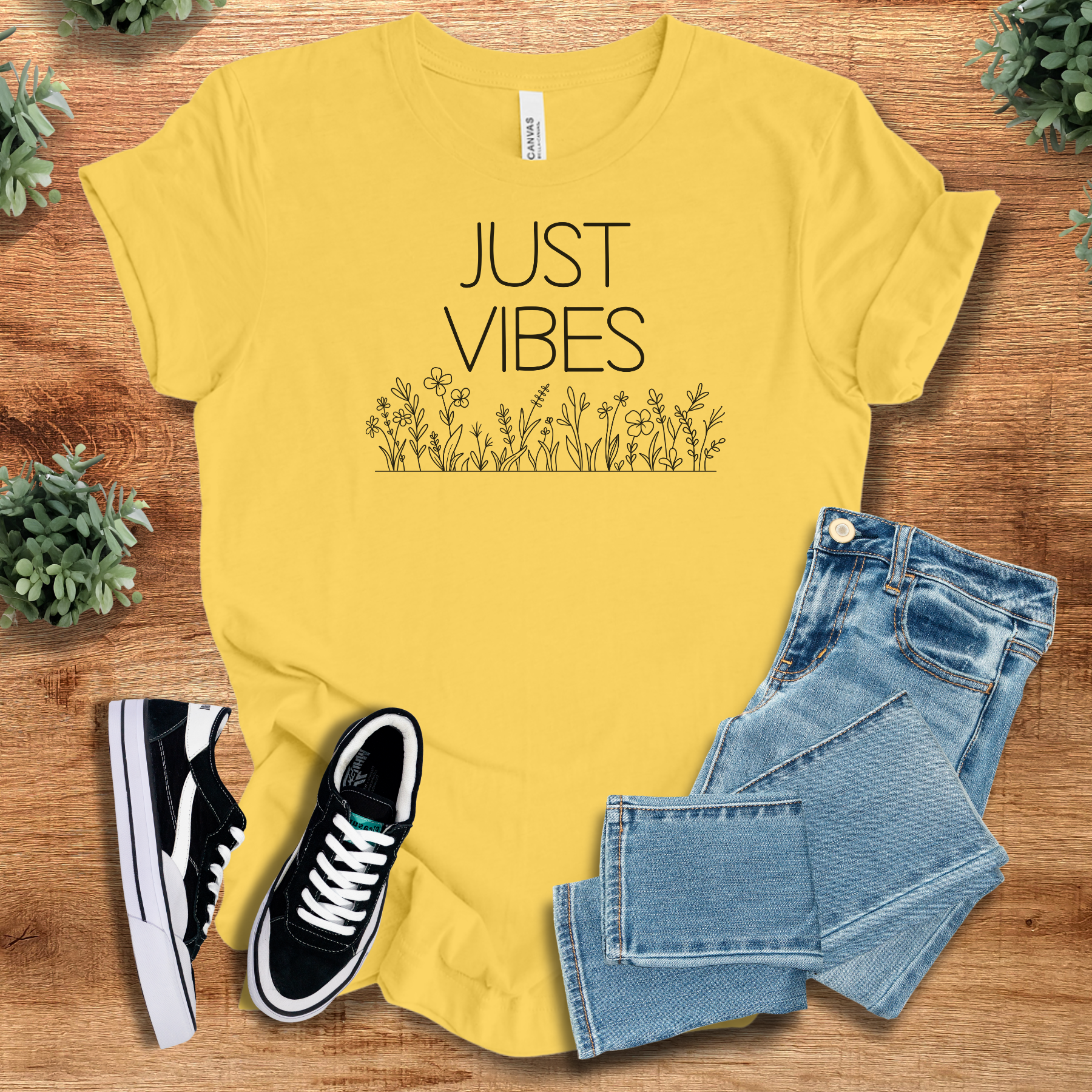 Just Vibes Wildflower T‑Shirt in yellow on soft Bella+Canvas 3001 fabric. Minimalist floral graphic tee styled with jeans and sneakers.