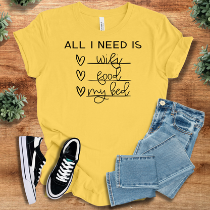 Military-green t-shirt with '' text, flat lay styled on a wooden surface.