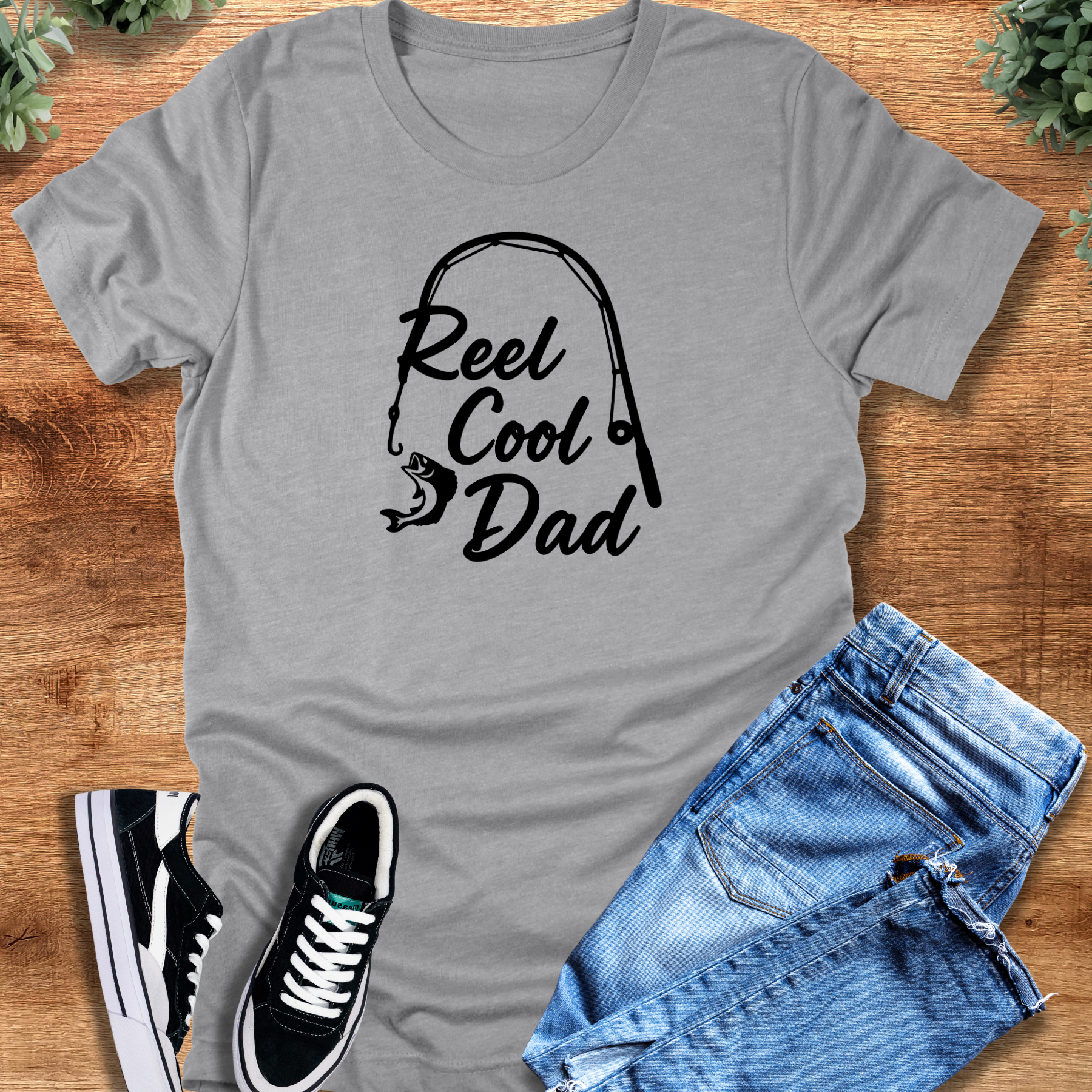 Military-green t-shirt with '' text, flat lay styled on a wooden surface.
