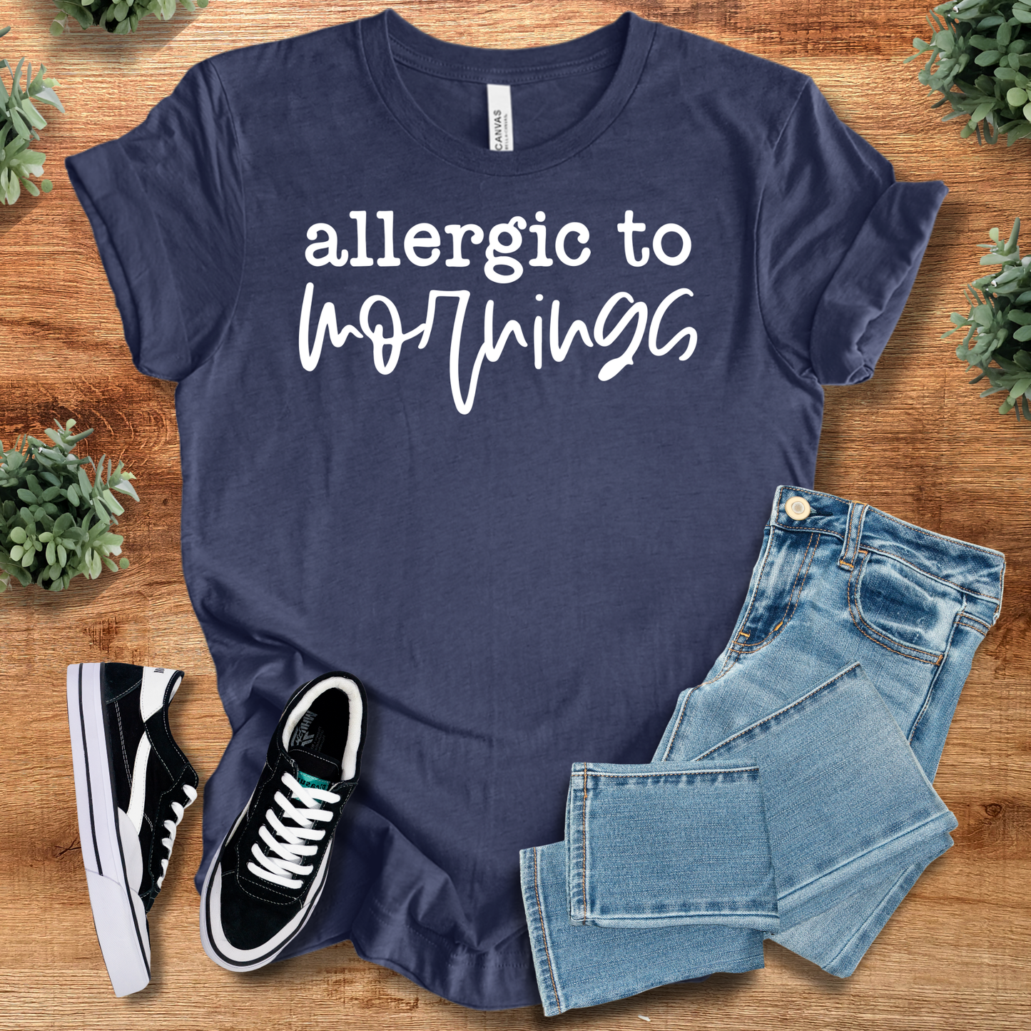 Heather-navy t-shirt with '' text, flat lay styled on a wooden surface.