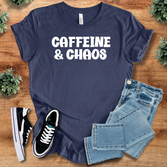 Heather-navy t-shirt with 'Caffeine & Chaos Unisex Tee' text, flat lay styled on a wooden surface.