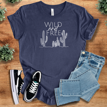 Heather-navy t-shirt with 'Wild And Free T‑Shirt' text, flat lay styled on a wooden surface.