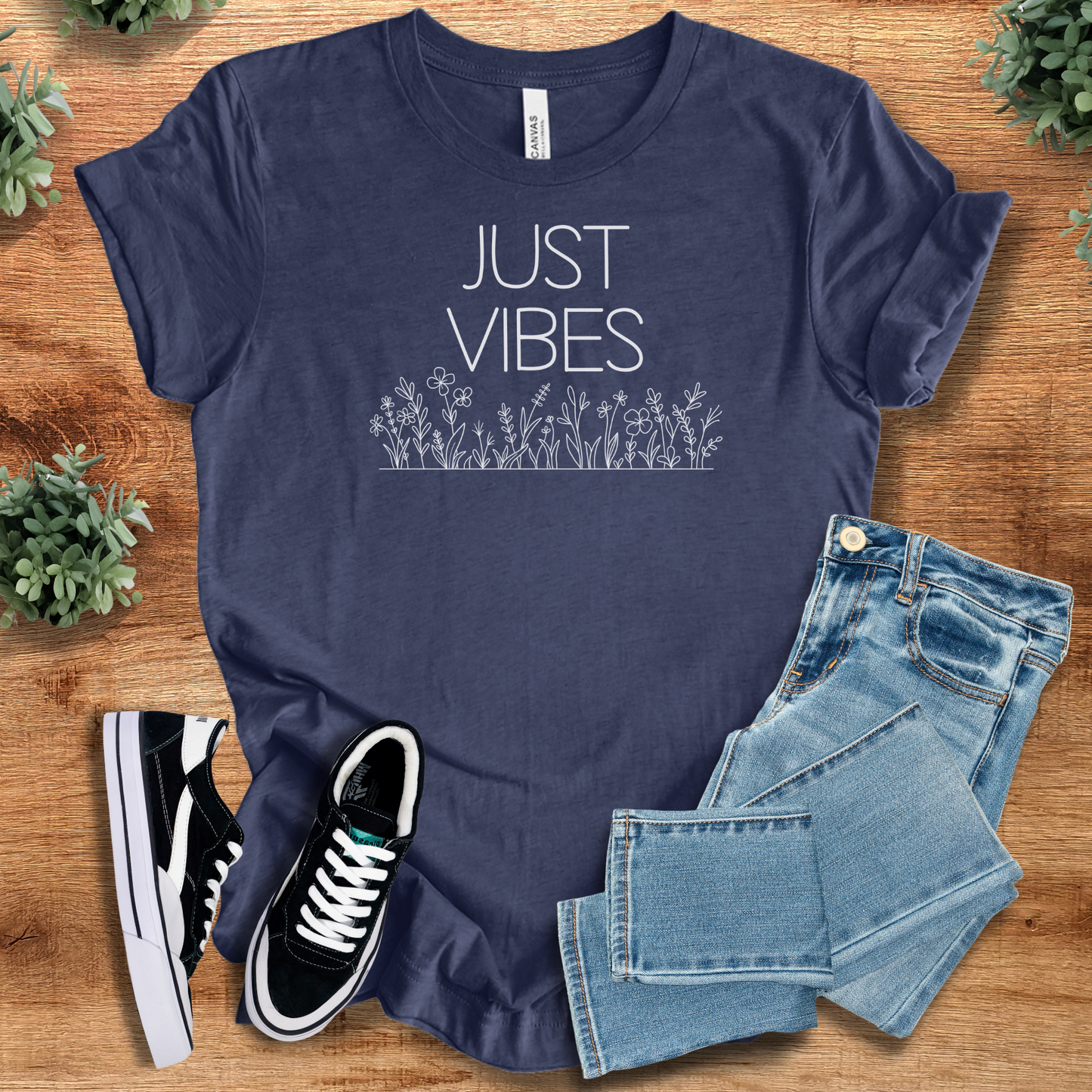 Just Vibes Wildflower T‑Shirt in navy blue Bella+Canvas 3001. Soft unisex graphic tee with floral design, paired with denim and sneakers.