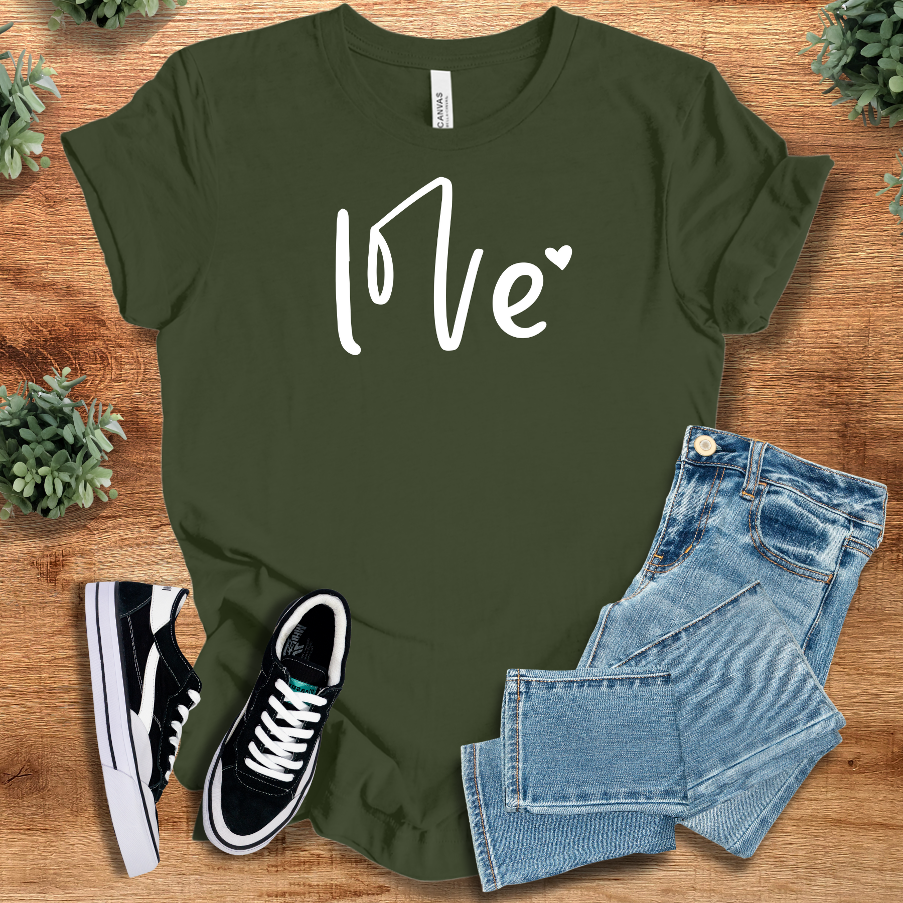 Pink t-shirt with '' text, flat lay styled on a wooden surface.