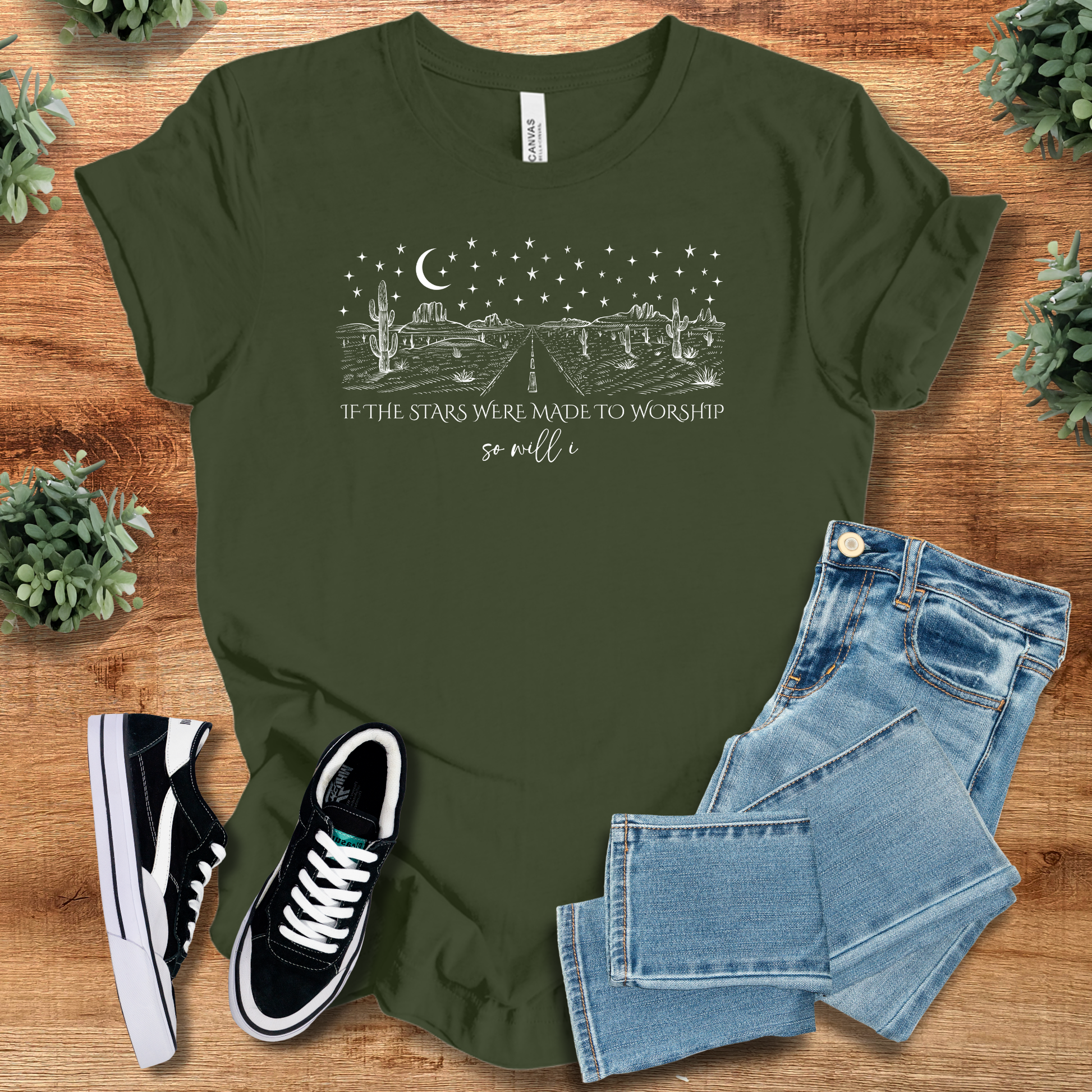 White t-shirt with '' text, flat lay styled on a wooden surface.