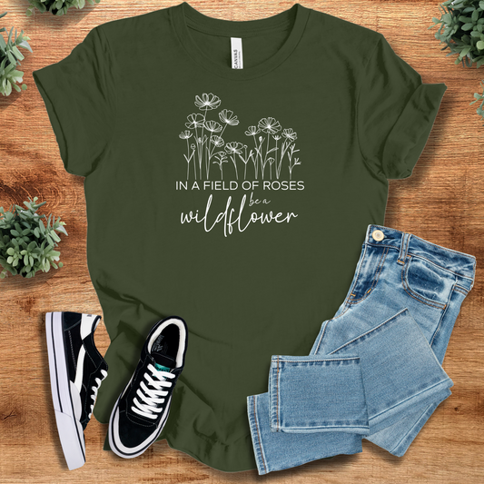 Olive green 'In A Field Of Roses, Be A Wildflower' T-shirt on soft Bella+Canvas 3001, styled with jeans and sneakers. Nature-inspired comfy tee.