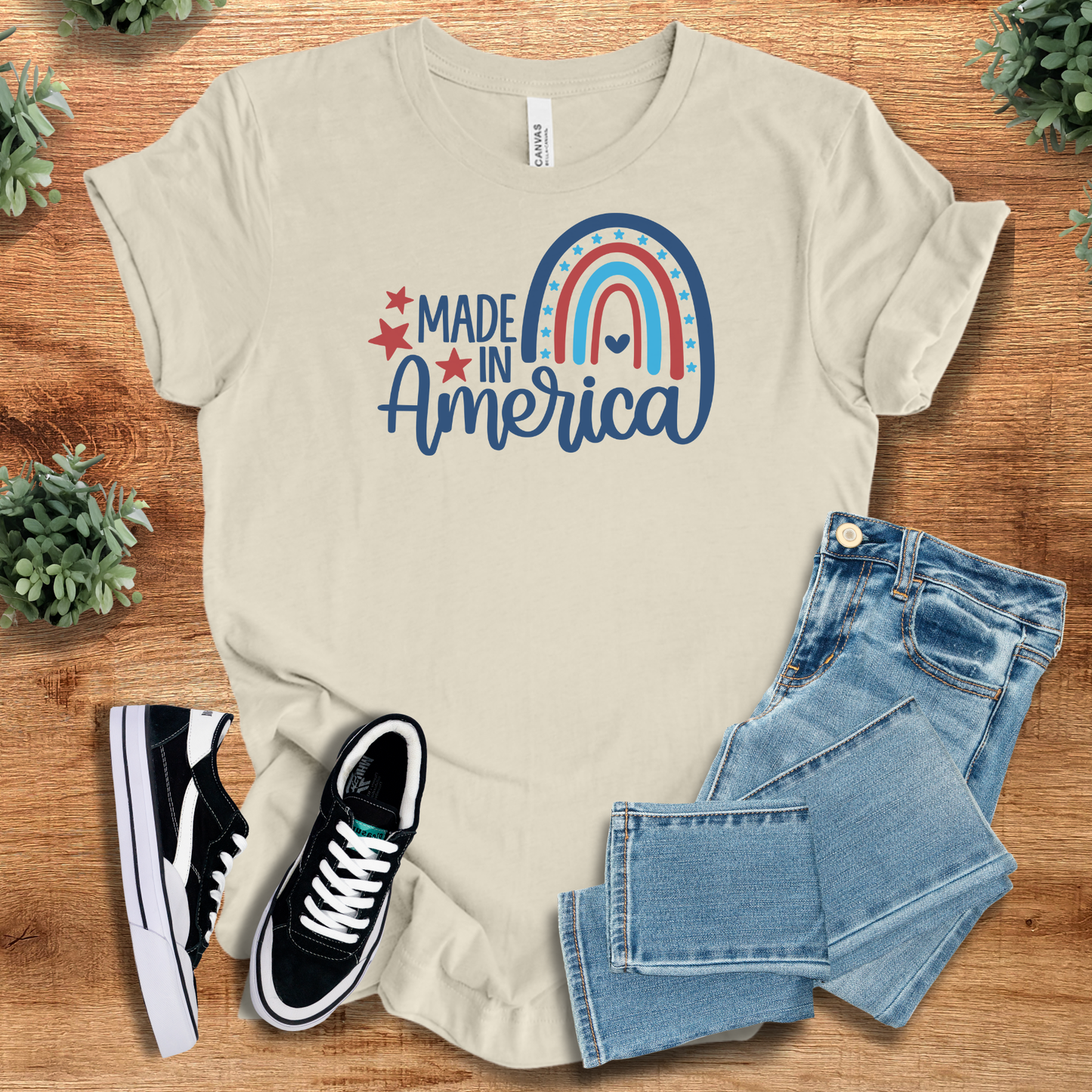 White t-shirt with '' text, flat lay styled on a wooden surface.