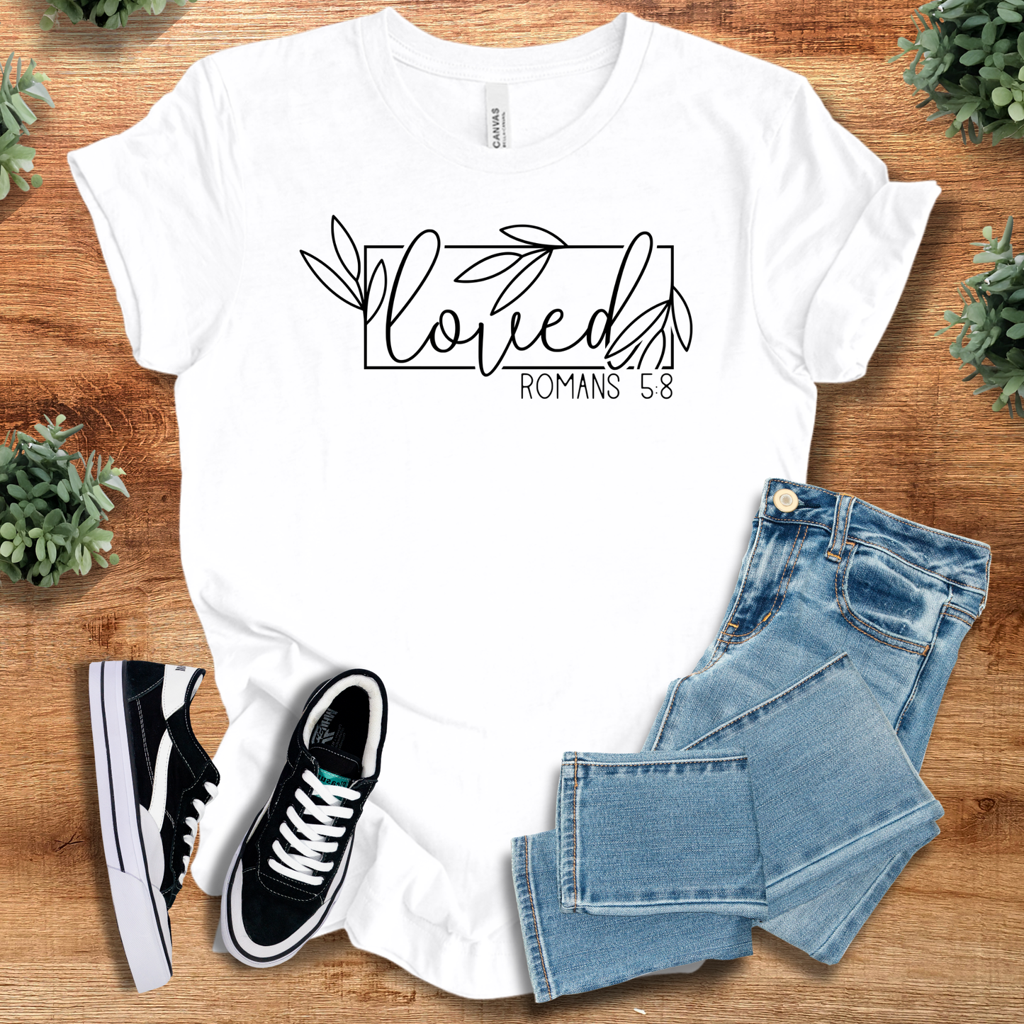 White Loved Romans 5:8 Christian Tee with minimalist floral lettering, unisex inspirational shirt paired with denim and casual shoes.
